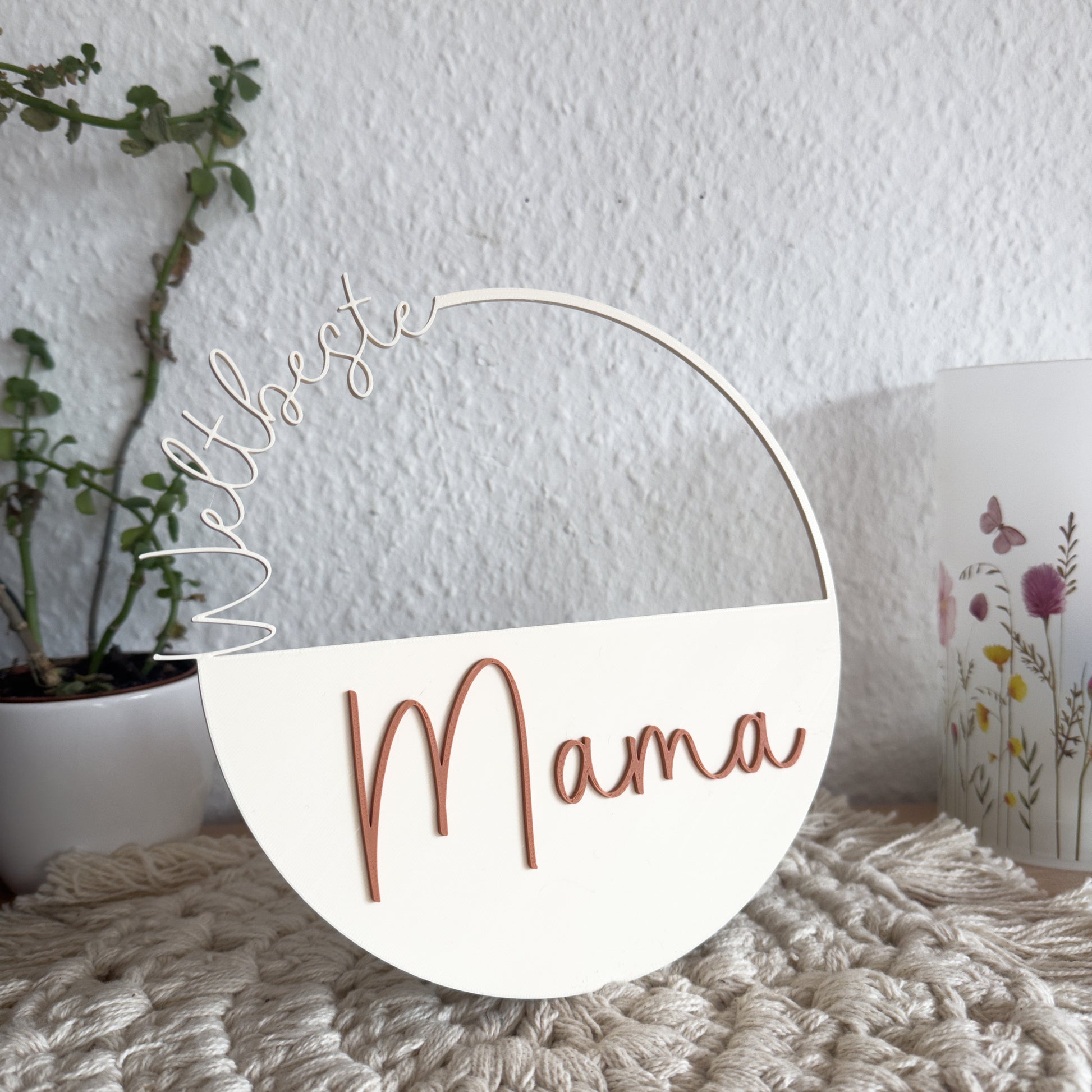 3D-gedrucktes Dekoschild Weltbeste Mama in Terracotta und Cremeweiß, Detailaufnahme der Schrift auf Makramee-Untergrund